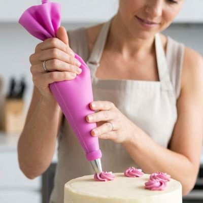 Pochage de crème au beurre sur un gâteau avec poche en silicone rose